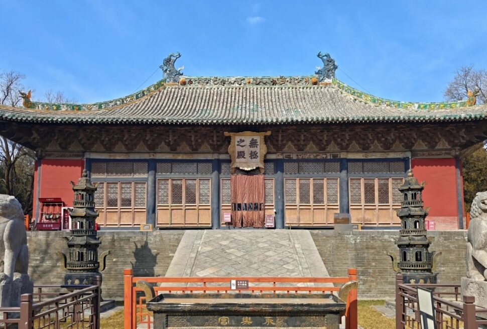 Traditional Chinese temple facade with ornate tiled roof, wooden doors, and stone guardian lions in front.Yongle Palace,Yuncheng,Shanxi