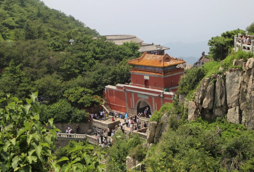 Ancient Chinese temple on Mount Hua surrounded by lush greenery and rocky cliffs.