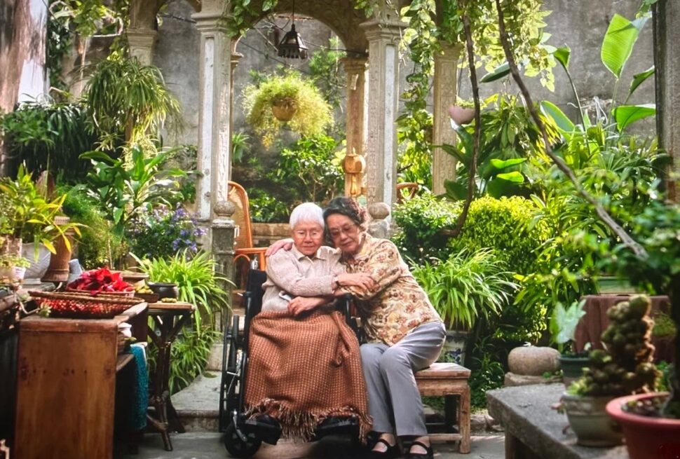 Chaoshan,Guangdong,Chinatravel A senior couple sitting together in a lush, green garden with traditional stone architecture.
