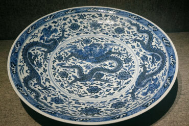 Blue and white porcelain plate with dragon motifs and floral patterns in circular design. (Decorative ceramic plate.)