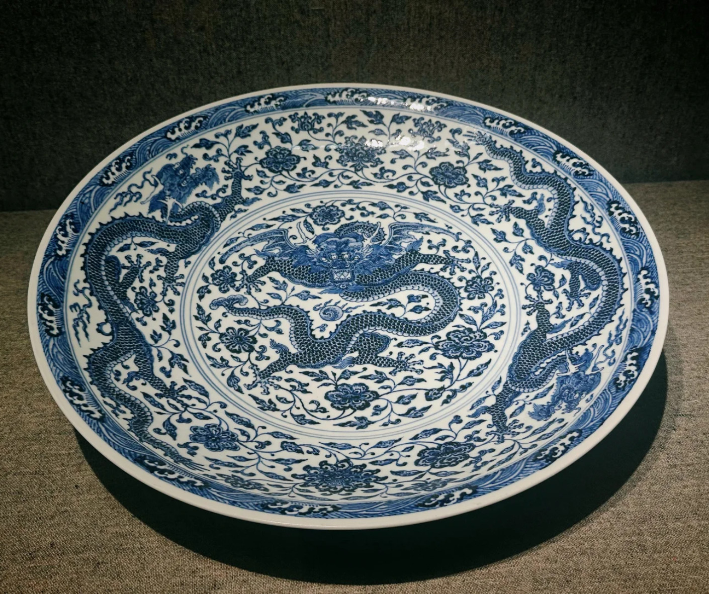 Blue and white porcelain plate with dragon motifs and floral patterns in circular design. (Decorative ceramic plate.)