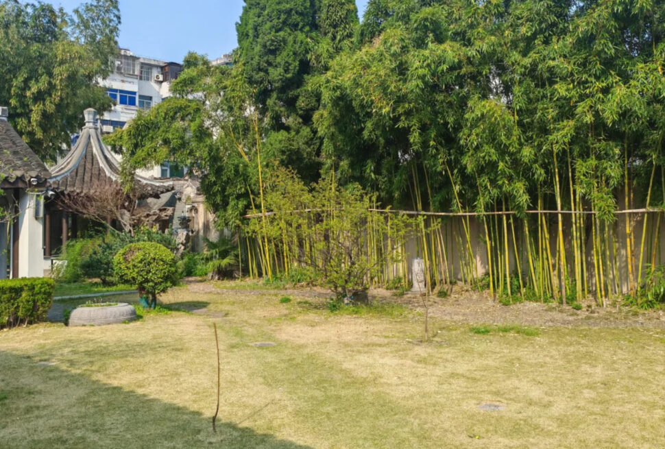 Garden scene with tall bamboo on the right and a traditional pavilion with curved roof on the left.