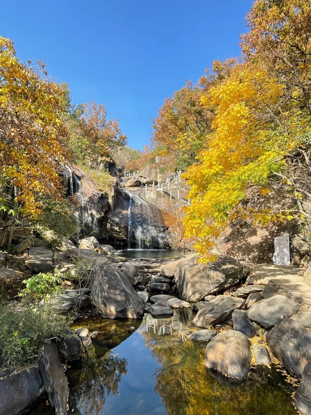 Autumn scene with waterfall, rocks, and colorful fall foliage in a natural park.