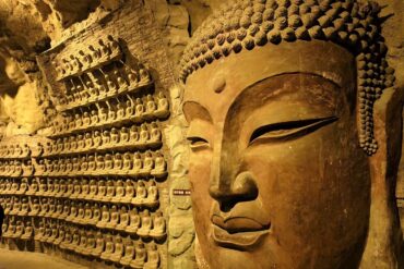 Thousand Buddha Mountain,Jinan,Chinatour Large Buddha head and numerous smaller Buddha statues in a cave temple.