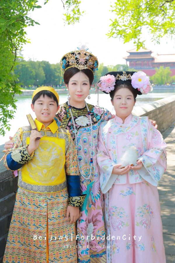 hanfu photoshoot, the forbidden city, beijing, qing dynasty, family, chinatrip, Three people in ornate traditional Chinese attire posing together outdoors by a river and temple buildings in the background.
