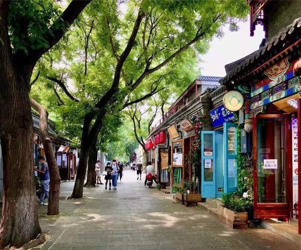 beijing, chinatravel, Pedestrian street lined with colorful shopfronts and a tree canopy, people strolling along the path.