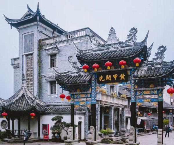 Tongliang Ancient Town,Chongqing,Chinatour Ornate Chinese paifang arch with blue-gold detailing and red lanterns in a temple courtyard