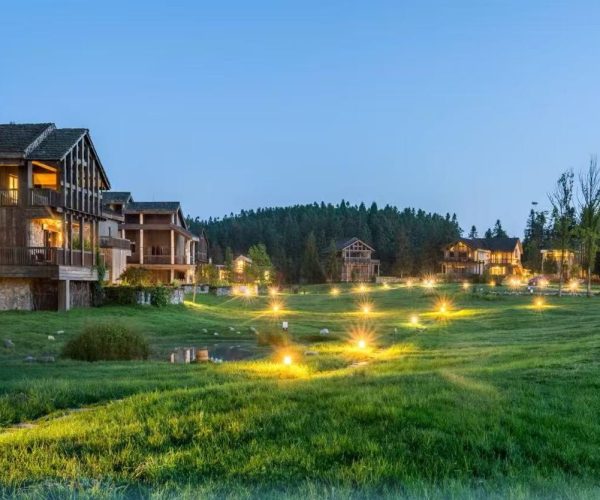 Nanshan Scenic Area,Chongqing,Chinatour Row of wooden cottages on a glowing green lawn with warm ground lights at dusk in a resort setting