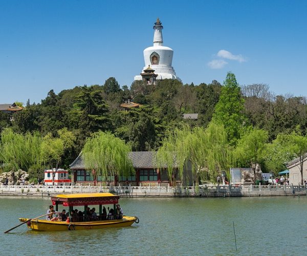 Beihai Park, beijing, chinatravel, Yellow tour boat carrying passengers glides on a calm lake with willows and a hillside temple/pagoda in the background.