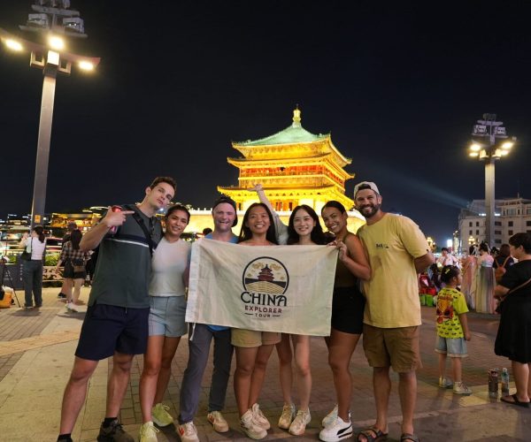 Xi'an Bell Tower with China Explorer Tour, china, china tour, Group of friends posing with a banner that reads 'China Explorer Tour' in front of a lit traditional pagoda at night.