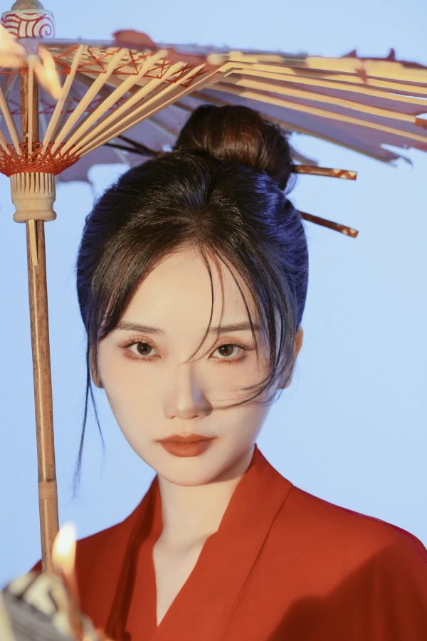 Hanfu Photoshoot Experience in China, chinatravel, female, Portrait of a woman in a red outfit holding a traditional paper parasol against a blue background.