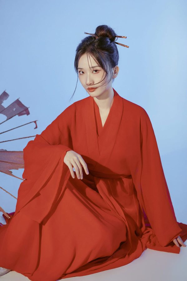 Hanfu Photoshoot Experience in China, chinatravel, female, Portrait of a woman in a red kimono-style robe against a light blue studio backdrop, looking at the camera.