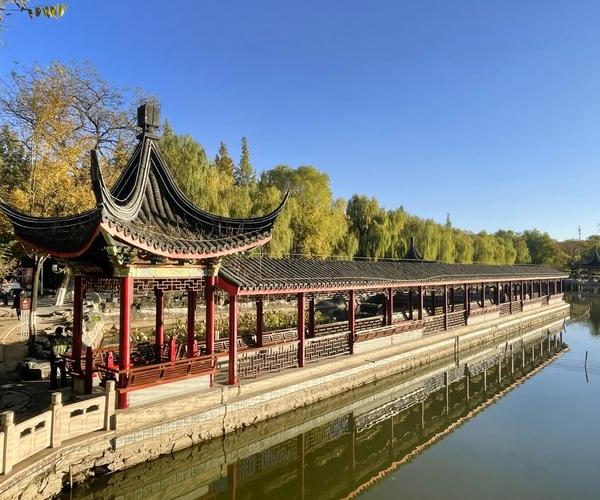 Beihai Park, beijing, chinatravel, Long covered Chinese pavilion with curved roof and red pillars beside a calm lake.