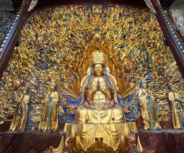 Baodingshan Temple,Chongqing,Chinatour Golden seated Buddhist deity with numerous outstretched arms, surrounded by many small golden figures in a shrine poster.