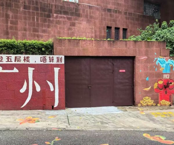 Yuexiu Park and Five Rams Statue,Guangzhou,Chinatour Red wall with large white Chinese characters beside a brown double gate; right side features a colorful mural with a water faucet and gold ingots.