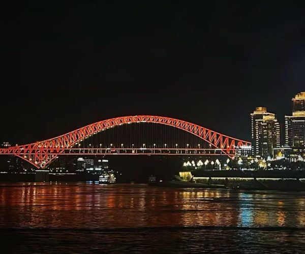Chaotianmen Dock and Riverside Promenade,Chongqing,Chinatour Night view of a red-lit arched bridge spanning a river, with a city skyline illuminated in the background