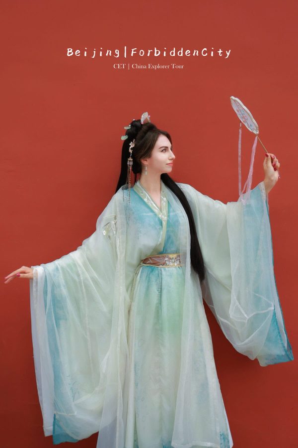 Hanfu photoshoot, Beijing, Imperial Ancestral Temple (Tai Miao), female, chinatravel, Woman in pastel blue traditional Chinese hanfu with long, flowing sleeves poses with a round hand fan against a red wall; beads in her hair and delicate accessories visible.