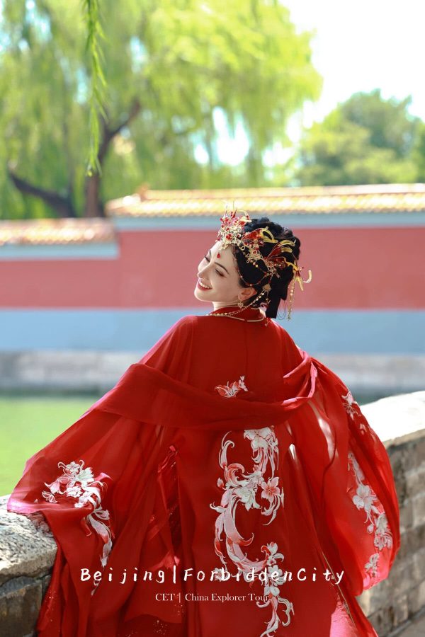 Hanfu photoshoot, the forbidden city, beijing, solo, chinatravel, Smiling woman in a red, embroidered traditional gown with an ornate gold headpiece, outdoors by a stone railing in Beijing (Forbidden City) on a tour poster.