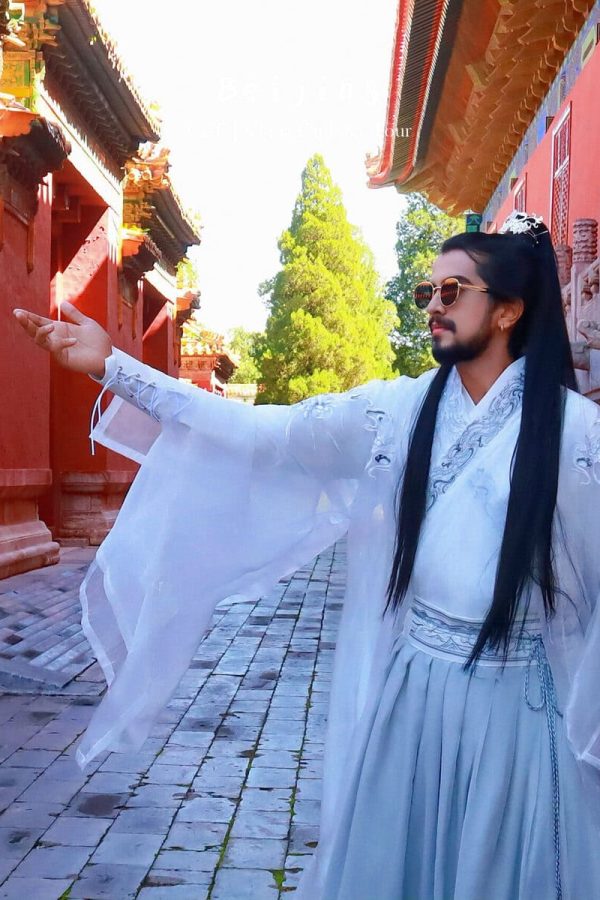 Hanfu photoshoot, Beijing, Imperial Ancestral Temple (Tai Miao), male, chinatravel, A man in a white traditional Hanfu with long black hair and sunglasses poses with one arm extended in a red temple courtyard with stone walls and carvings.