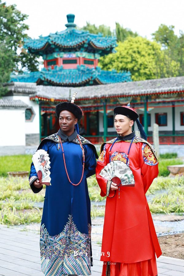 Hanfu Photoshoot, Beijing, Zhongshan park, male, friends, chinatravel, Two men in ornate traditional Chinese robes (blue and red) holding decorative fans, posing outdoors with a colorful pagoda in the background.