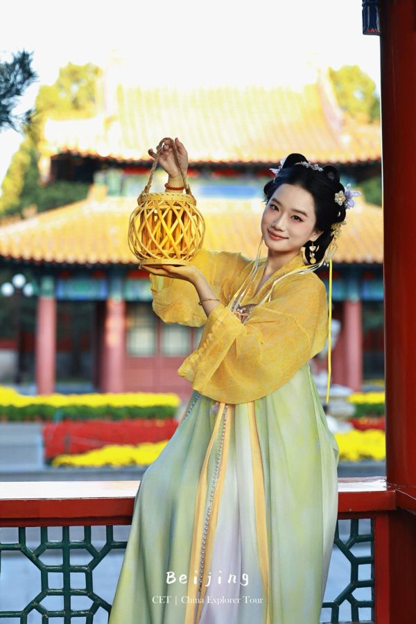 Hanfu photoshoot, the forbidden city, beijing, chinatravel, Woman in yellow hanfu holding a woven lantern at a Beijing temple courtyard, colorful background flowers and traditional roof.