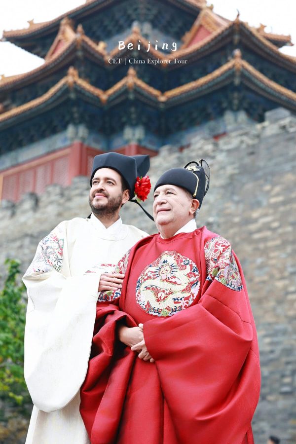 Hanfu Photoshoot, Beijing, Forbidden City Exterior, friends, chinatravel, Two men in traditional Chinese ceremonial robes pose together outdoors in front of an ornate temple with red walls and gold-tiled roof, one wearing white and the other red with a dragon embroidery motif.