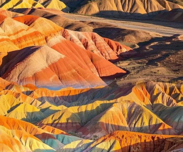 Rainbow Danxia Adventure,Zhangye,China tour Vibrant layered hills in reds, oranges, yellows, greens and blues forming a rainbow landscape. Aerial view of colorful badlands.