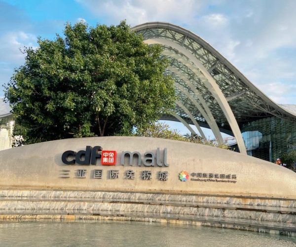 Sanya International Duty Free Shopping Center,Sanya,Chinatravel Large curved canopy of a modern mall with a water feature and a sign reading 'cdf mall' in English and Chinese characters, with trees in the background.