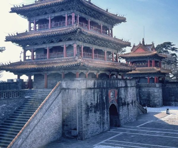 Dongling Park,Shenyang,China tour Three-tier Chinese pagoda atop a stone fortress wall with staircases and a smaller building nearby under a clear blue sky