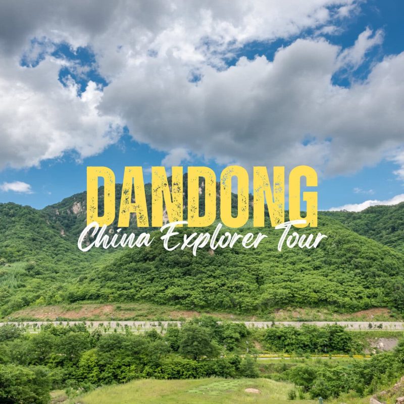 Dandong,Liaoning,China tour Lush green hills under a blue sky with clouds; bold yellow 'DANDONG' and white cursive 'China Explorer Tour' text overlaying the landscape