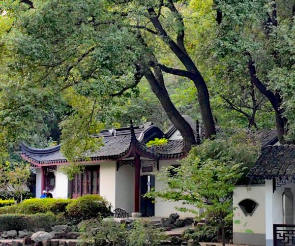 Tinglin Park,Kunshan,China tour Traditional Chinese garden with a white pavilion, curved tiled roofs, and a calm reflecting pond among trees and rocks.