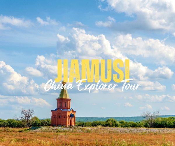 Jiamusi,Heilongjiang,Chinatravel Promotional banner over a rural field with a small brick church; text reads 'JIAMUSI China Explorer Tour' in yellow and white.