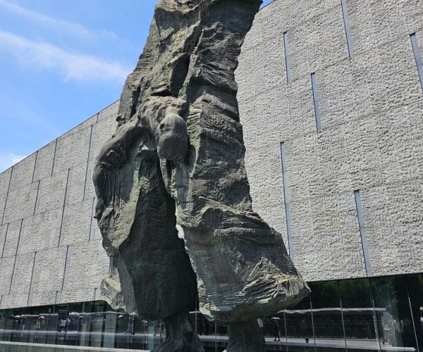 Memorial Hall to the Victims in the Nanjing Massacre,Nanjing,China tour Tall dark sculpture of a distorted humanoid figure on a pedestal outside a textured modern building, titled 'Family Ruined' Tall dark sculpture of a distorted humanoid figure on a pedestal outside a textured modern building, titled 'Family Ruined'