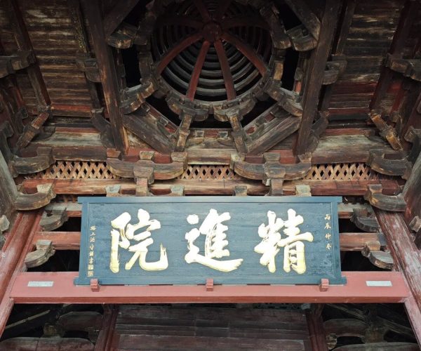 Baoguo Temple,Ningbo,Chinatravel Interior of a traditional Chinese wooden temple ceiling with a circular central wheel-like vent and a blue sign with gold Chinese characters below it