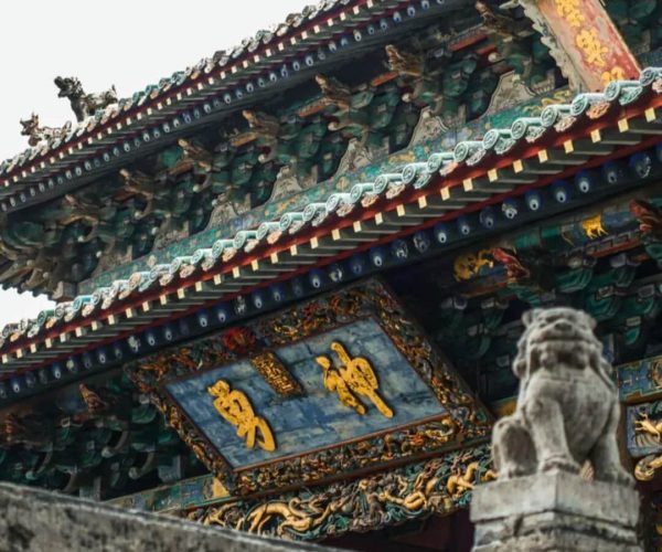 Xièzhou Guandi Temple,Yuncheng,Chinatravel Ornate temple roof with colorful dragons and tiles; a blue plaque with gold Chinese characters hangs under the eaves.