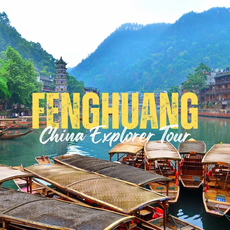 Fenghuang,Hunan,Chinatravel FENGHUANG China Explorer Tour banner over a riverfront with wooden boats and green hills in the background.
