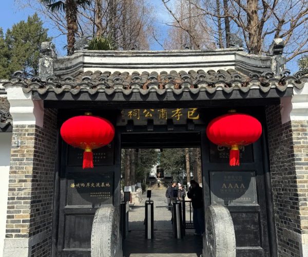 Memorial Temple of Lord Bao,Hefei,China tour Traditional Chinese gate with red lanterns and dark brick walls, leading to a tree-lined courtyard.