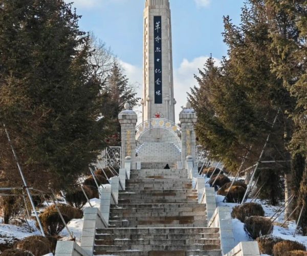 Beishan Park,Jilin,Chinatrip Stone stairway climbs to a tall stone monument with a red star at the top, framed by evergreen trees in a snowy landscape.