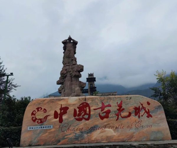 Beichuan Qiang City Tourist Area,Mianyang,Chinatravel Large stone sign with red Chinese characters reading 'Chinese ancient castle of China' in front of a tall rock sculpture and a small pagoda, on a paved plaza with steps leading up.