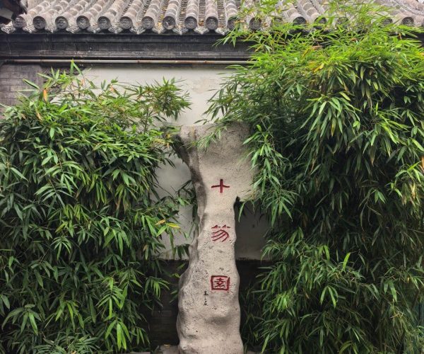 Shihu Garden,Weifang,China tour Stone stone monument with red Chinese characters, set in a bamboo-filled courtyard in front of a traditional tiled roof wall.