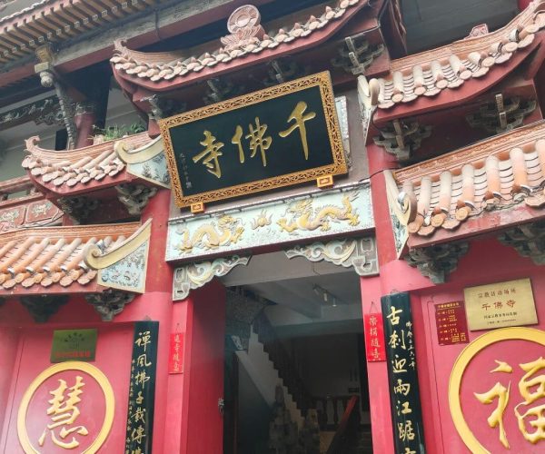 Qianfo Temple,Jinan,China tour Red Chinese temple entrance with ornate roof tiles and gold plaque above the doorway; dragons and traditional carvings adorn the facade.