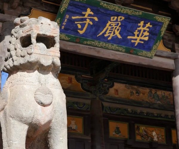 Huayan Temple,Datong,Chinatravel Stone guardian lion statue beside a Chinese temple doorway with a blue signboard of gold characters.