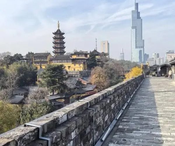 Nanjing City Wall,Nanjing,China tour Stone city wall walkway overlooking a pagoda and traditional buildings on the left, with a distant modern skyline on the right.