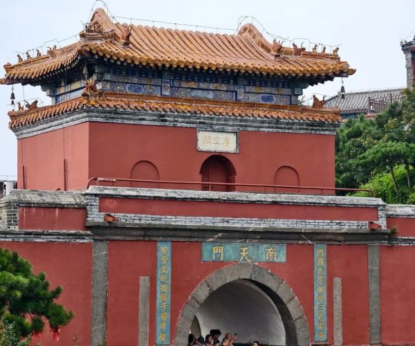 South Gate to Heaven,Tai'an,China tour Red traditional Chinese gate with a tiled, upturned roof and blue decorative bands, crowds entering a courtyard temple area