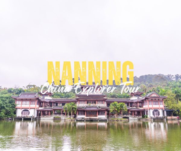 Nanning,Guangxi,Chinatravel Traditional Chinese-style building complex on a calm lake with trees and hills in the background, overlaid by large yellow 'NANNING' and white script text 'China Explorer Tour'.