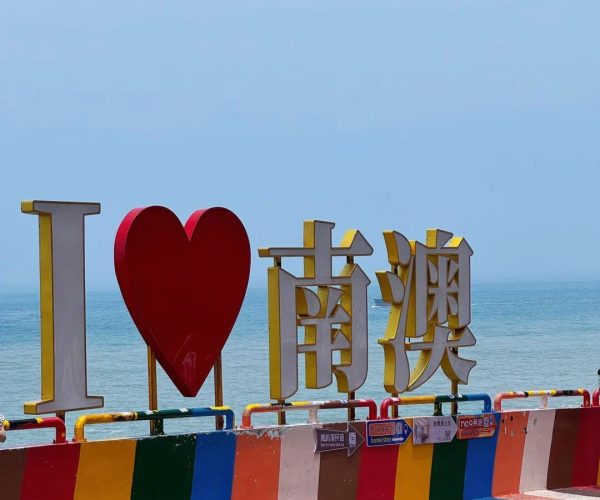 Nan'ao Island,Shantou,Chinatravel Colorful seaside display with a large 'I ♥' sign followed by big Chinese characters, beside a rainbow-striped walkway by the ocean.