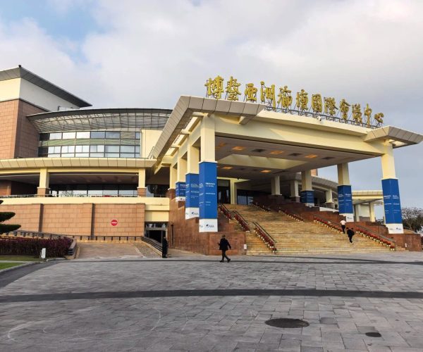 Bo’ao Forum for Asia Conference Center,Qionghai,Chinatravel Large modern convention center with a curved glass facade, gold Chinese characters on the roof, and a wide staircase with blue banners.