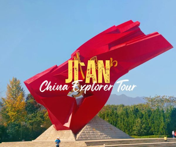 Ji'an,Jiangxi,China tour Red, abstract sculpture against a blue sky with trees in the background; overlaid text says 'JIAN China Explorer Tour'.