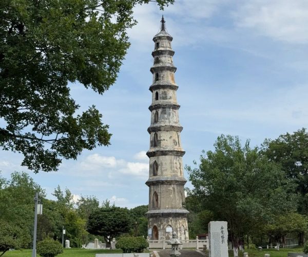 Jizhou Kiln Site,Ji'an,China tour Tall multi-tier stone pagoda in a green park, with trees and a clear blue sky in the background.