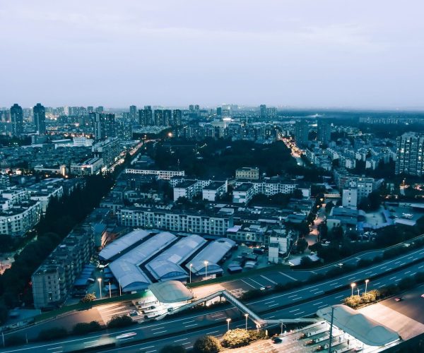 Sichuan,Chinatravel Aerial view of a sprawling city at dusk, with a curving highway in the foreground and dense apartment blocks beyond.